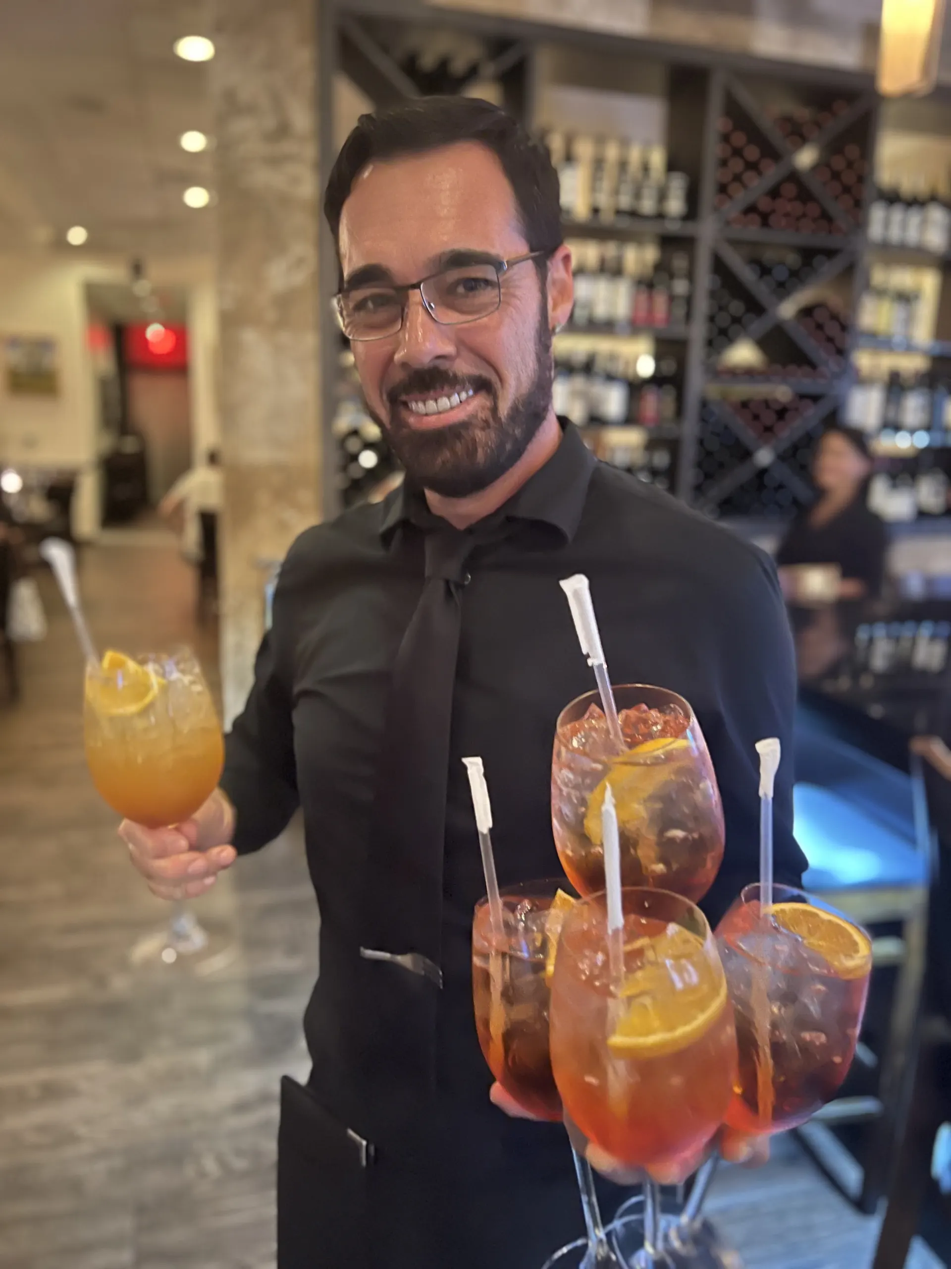 Server carrying Aperol Spritz cocktail at Vincenzo happy hour Orlando